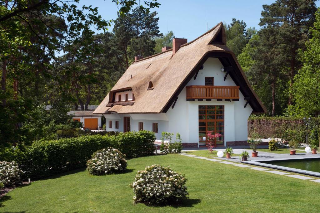 une maison avec un toit de chaume et une cour dans l'établissement Schmeling Haus Bad Saarow, à Bad Saarow