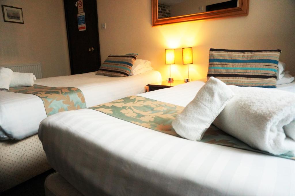 ein Hotelzimmer mit 2 Betten und Handtüchern in der Unterkunft Greyfriars Lodge Canterbury in Canterbury