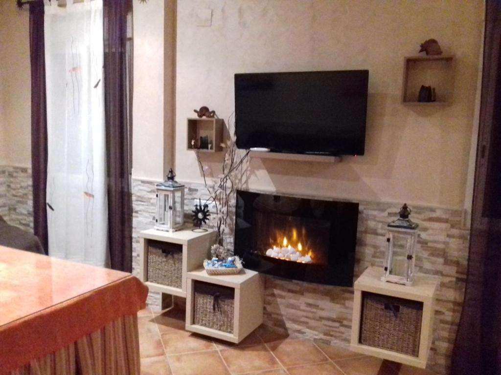 a living room with a fireplace and a flat screen tv at La Candelita in Majaneque