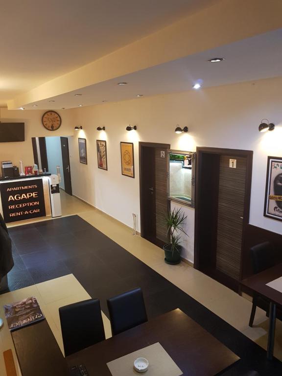 a waiting room with tables and chairs and a clock on the wall at Apartments Agape in Belgrade