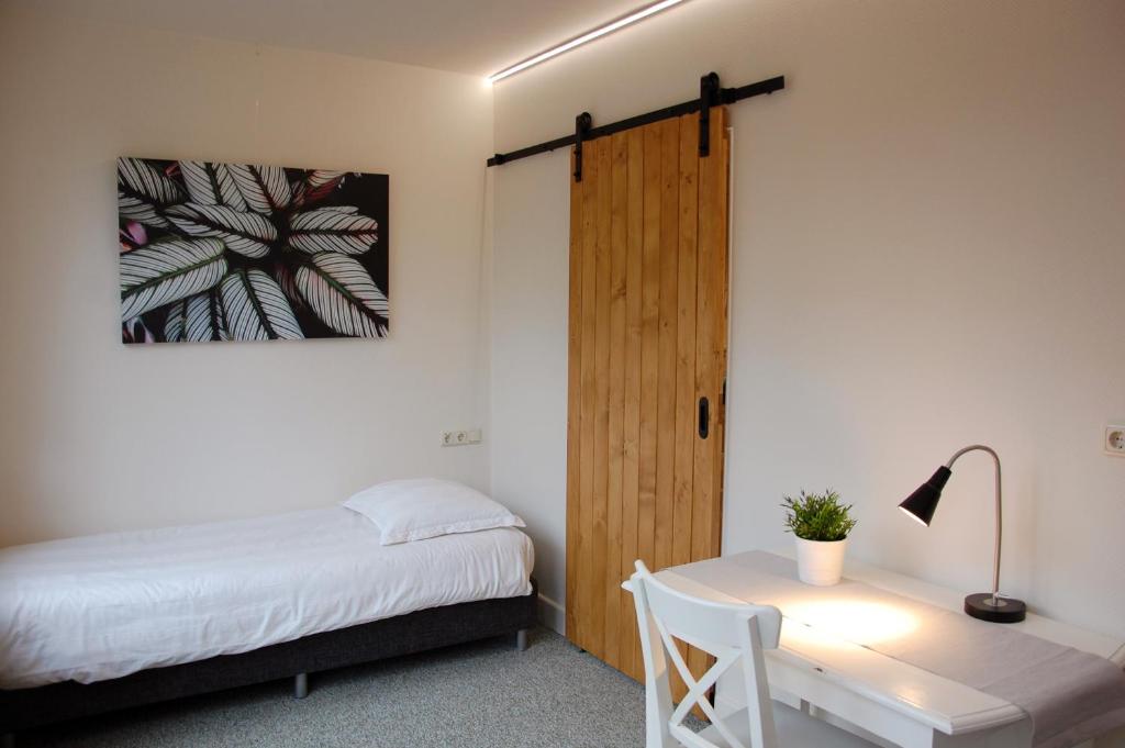 een slaapkamer met een bed, een bureau en een deur bij Central-Day Inn in Enschede