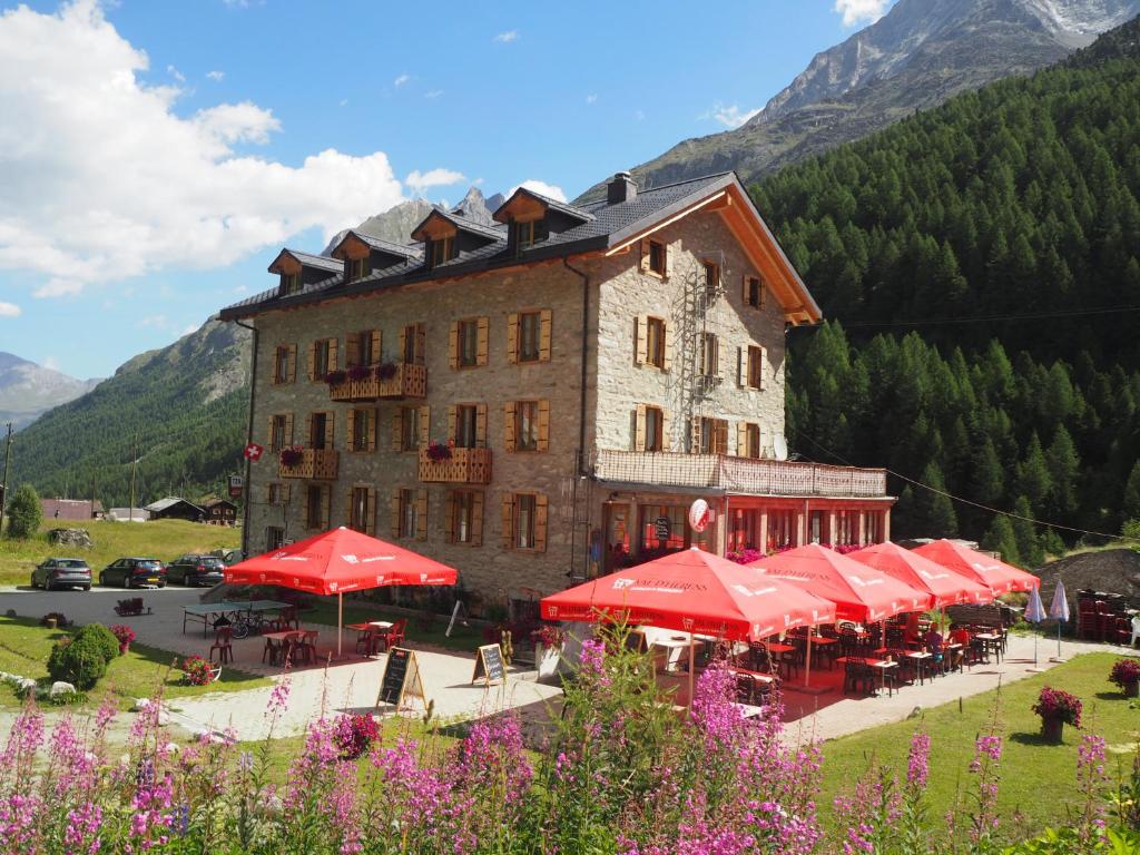 ein großes Gebäude mit roten Sonnenschirmen davor in der Unterkunft Aiguille de La Tza in Arolla