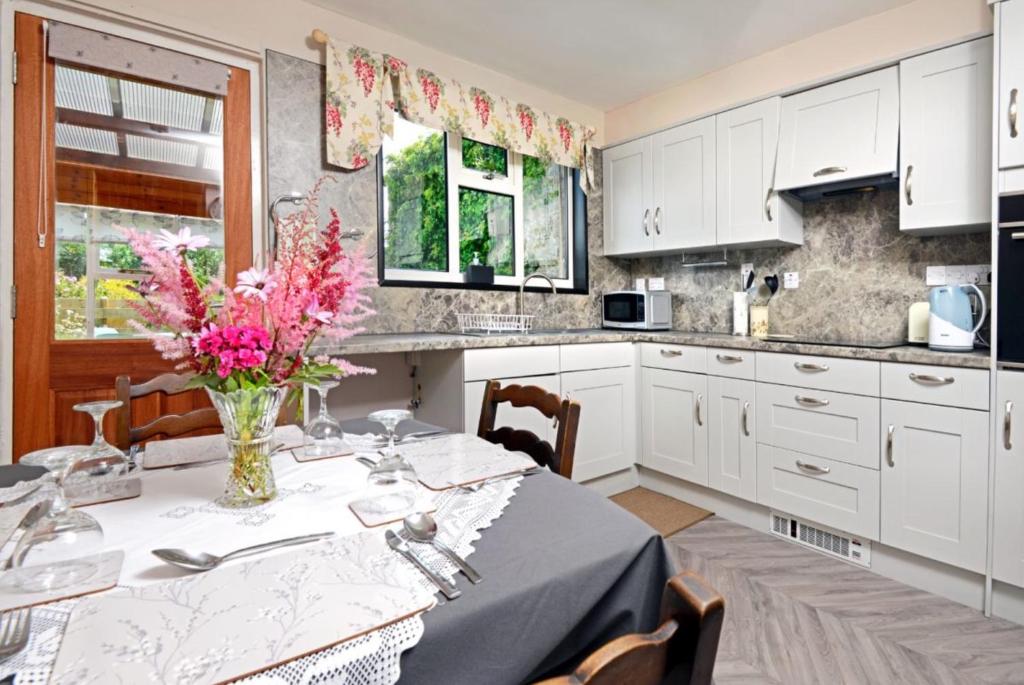 a kitchen with a table with a vase of flowers on it at Granny’s Cottage in Newcastleton