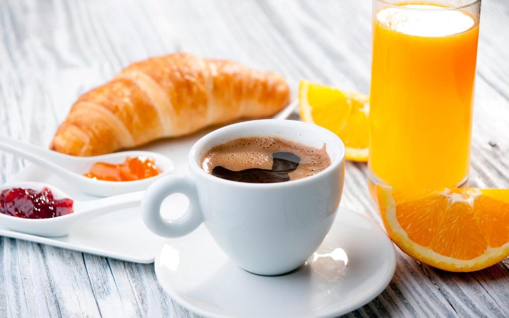 a cup of coffee and a plate of fruit and orange juice at La Petite Bérais in Missillac