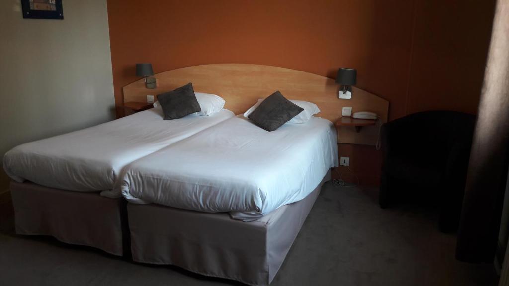 2 camas en una habitación de hotel con sábanas y almohadas blancas en Le relais de l'Argoat, en Belle-Isle-en-Terre