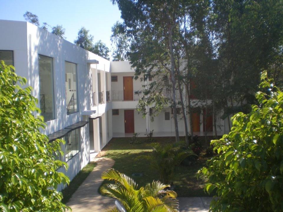 an exterior view of a white building with trees at Ruta Del Sol in Ypacarai