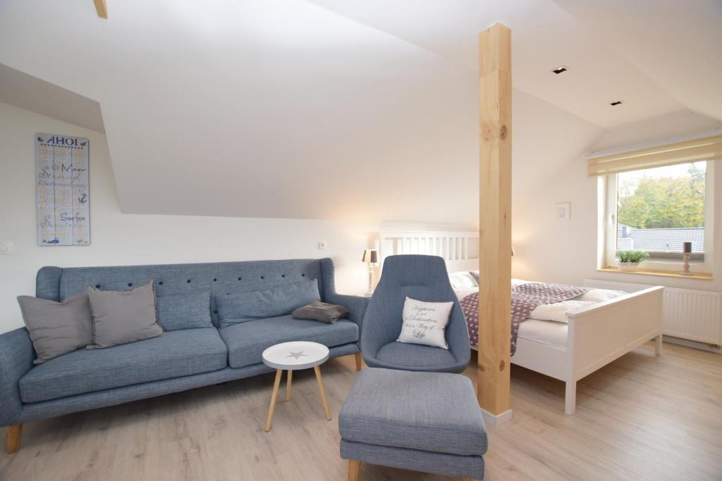 - un salon avec un canapé bleu et un lit dans l'établissement Ferienwohnung Ostseelys, à Glücksburg