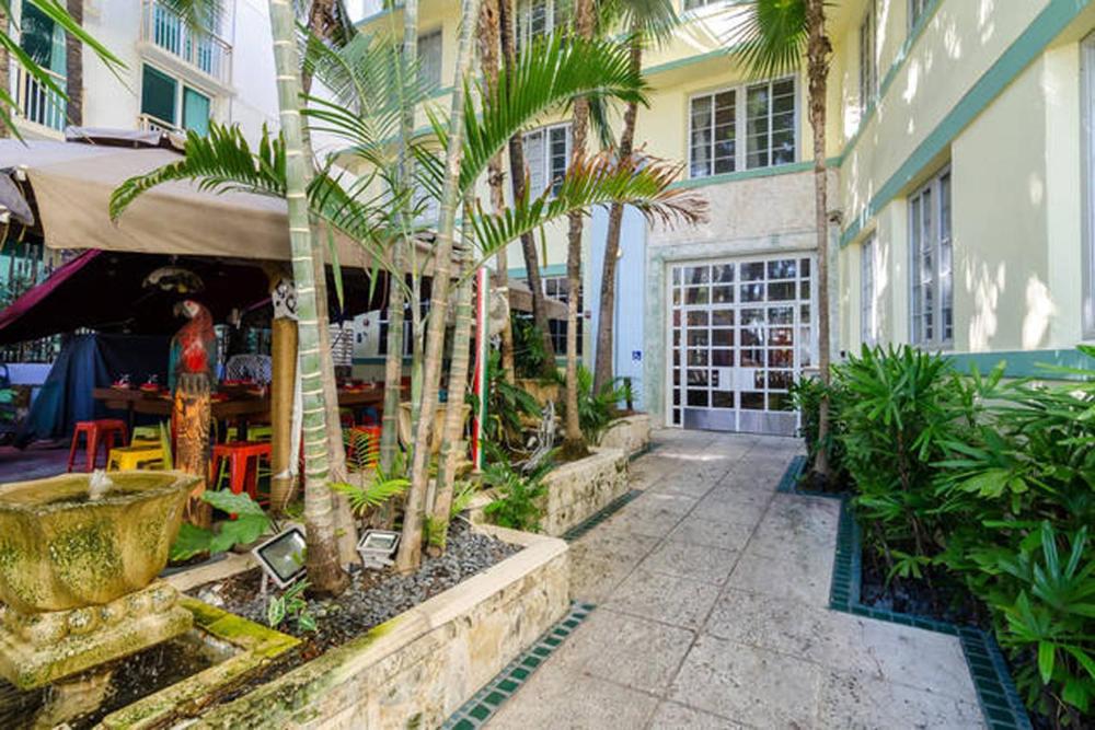 een binnenplaats met palmbomen en een gebouw met een restaurant bij Ocean Drive Studio Historic Building minutes walk to the Beach. in Miami Beach