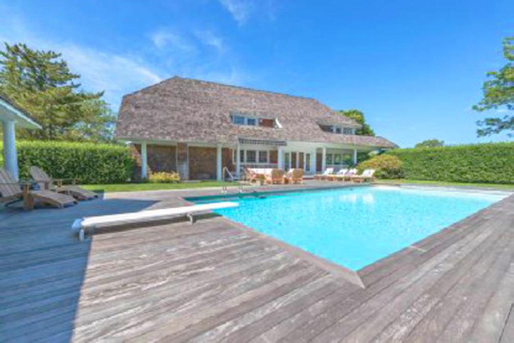 a home with a swimming pool and a house at Villa Victoria - Cozy Hamptons Villa in Bridgehampton