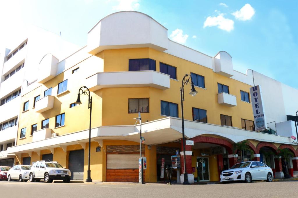 un edificio amarillo con coches estacionados frente a él en Hotel Madero en Villahermosa