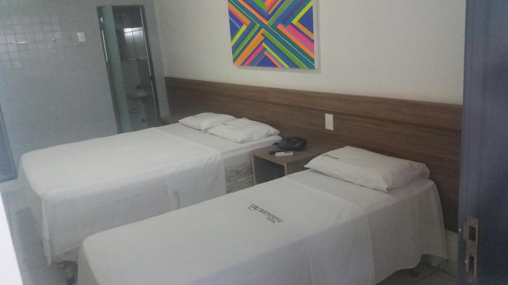 a room with two beds and a painting on the wall at Sambura Hotel in Feira de Santana