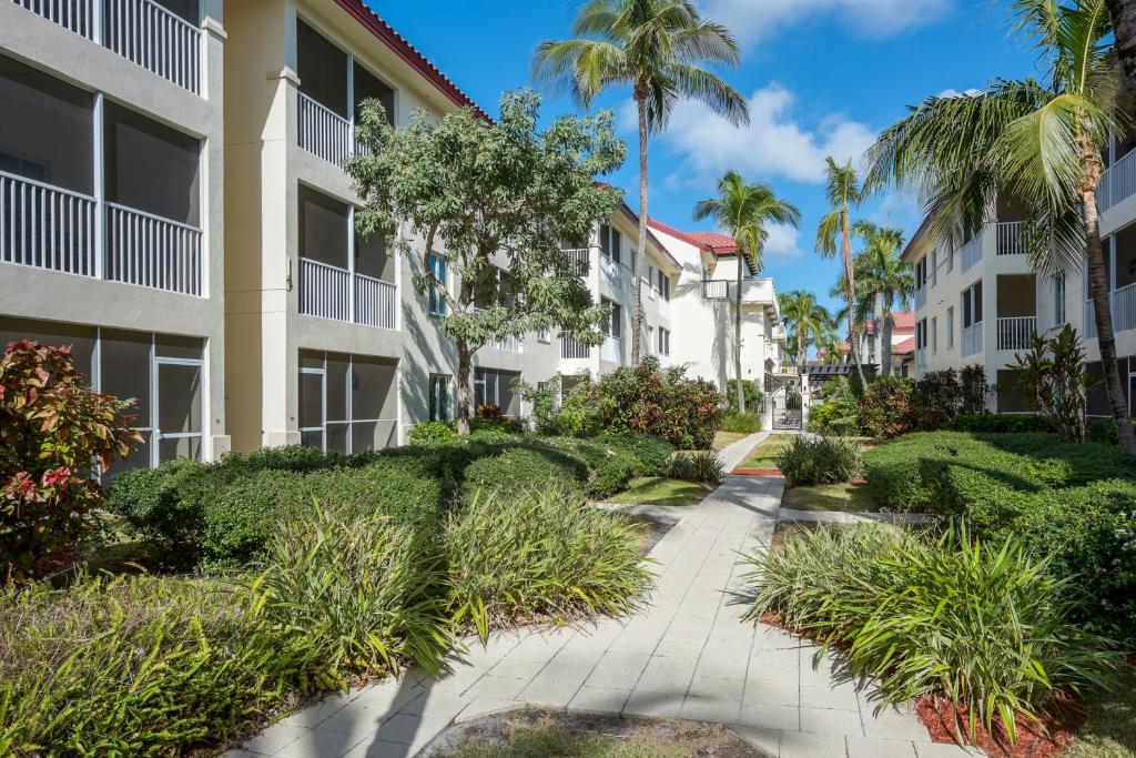 a walkway through the courtyard of a building with palm trees at Bellasera Resort in Naples