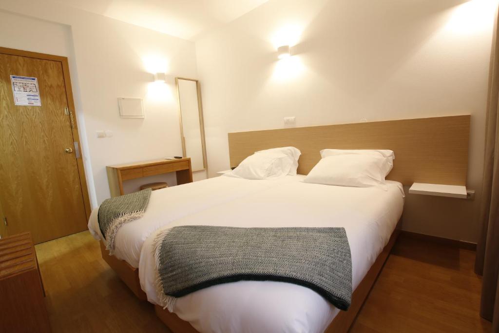 
a hotel room with two beds and two lamps at Baixa Hotel in Bragança
