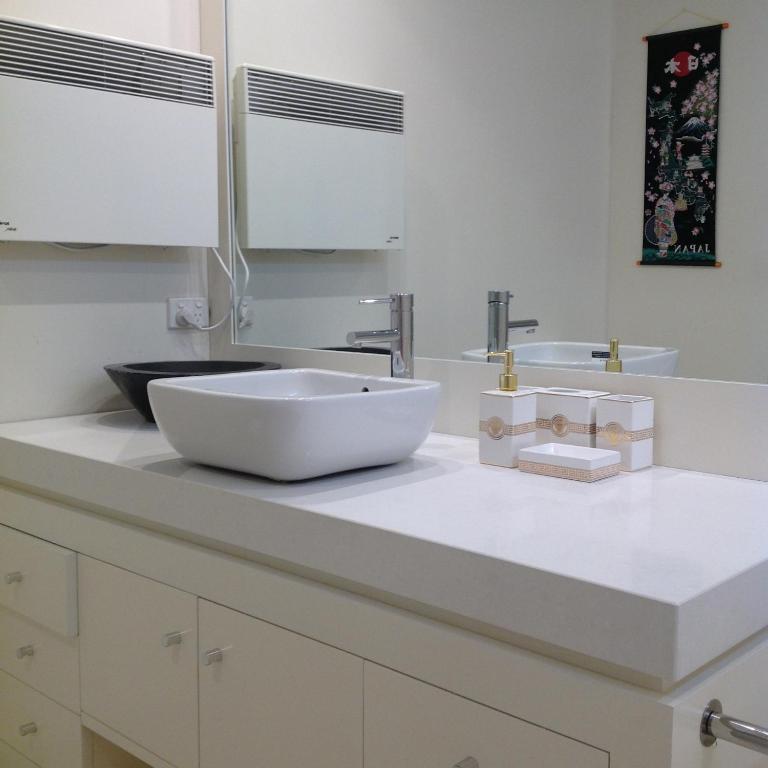 a white bathroom with a sink and two mirrors at Lorne Holiday House in Lorne