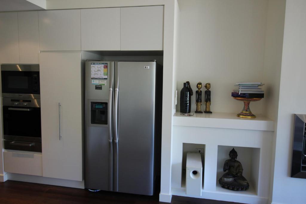 a kitchen with a stainless steel refrigerator next to a fireplace at Lorne Holiday House in Lorne