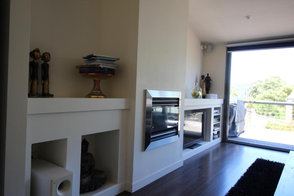 a living room with a fireplace and a tv at Lorne Holiday House in Lorne