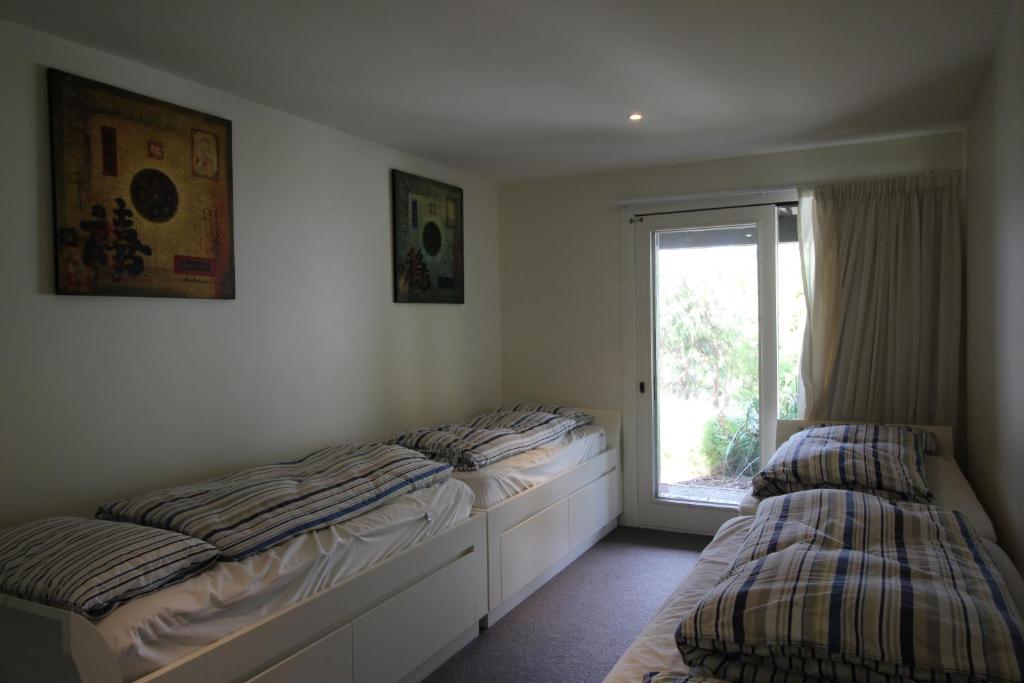 two beds in a room with a window at Lorne Holiday House in Lorne