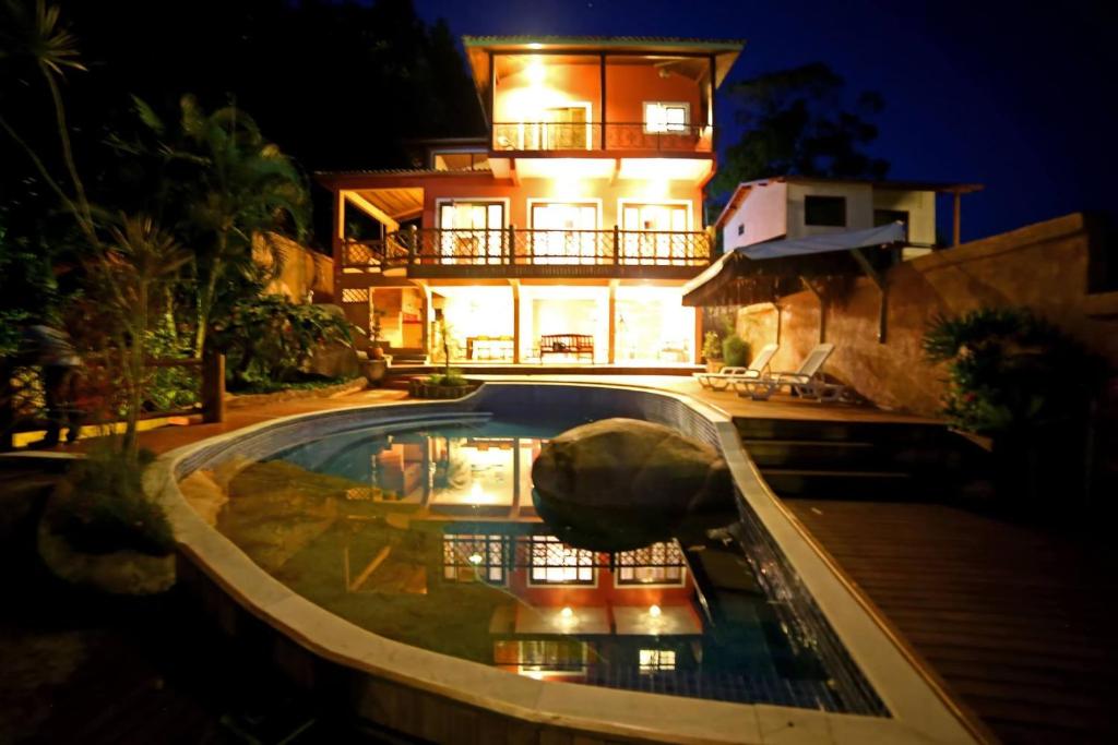 una casa con piscina frente a un edificio en Memorial Ilhabela residencial, en Ilhabela