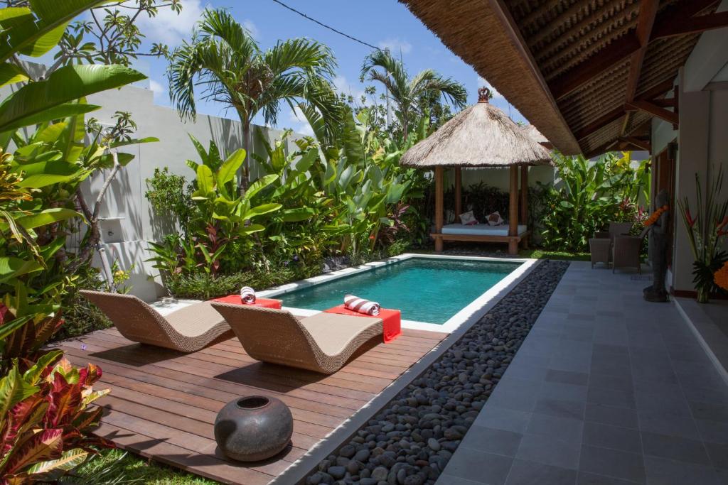 einen Pool in einem Garten mit zwei Stühlen und einem Pavillon in der Unterkunft Villa Kakariki in Kerobokan