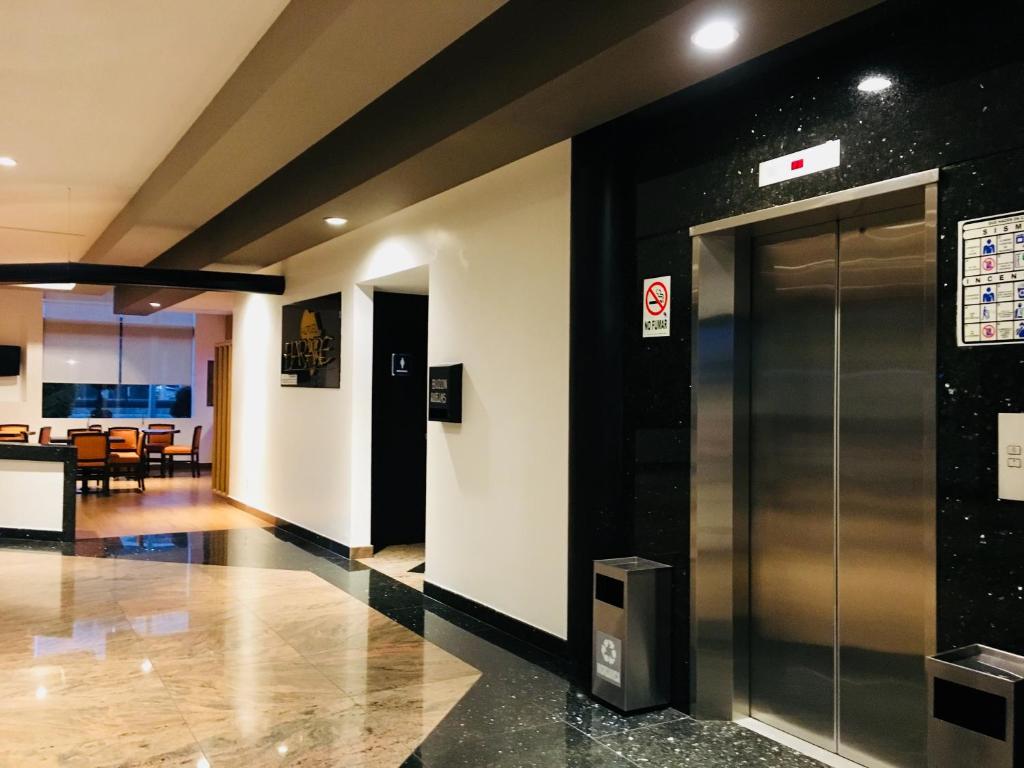A polished hotel corridor with elevators beside a seating and dining area.