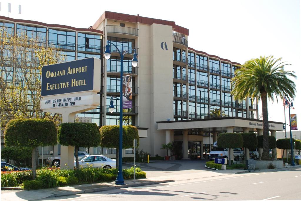 een groot gebouw met een bord ervoor bij Oakland Airport Executive Hotel in Oakland
