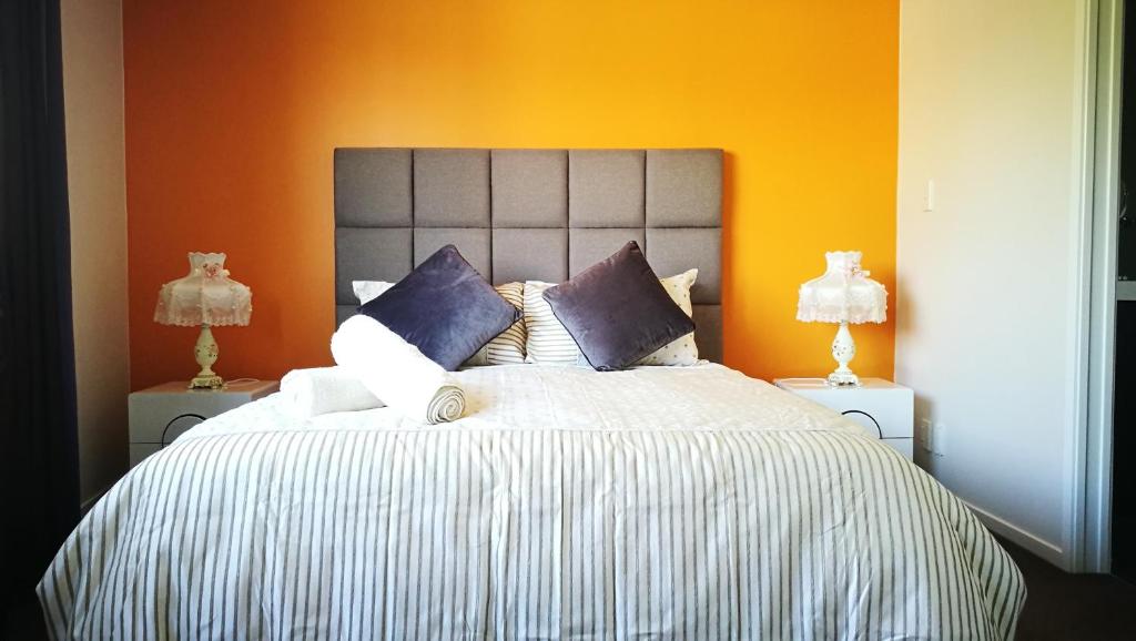 a bedroom with a large bed with an orange wall at The Heart of Rotorua in Rotorua
