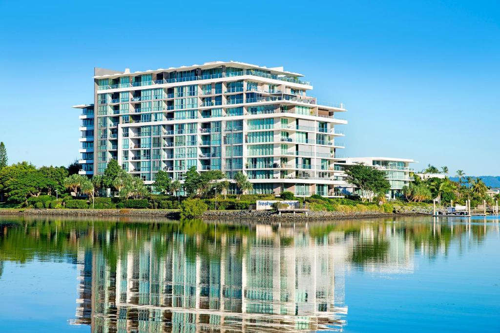 un grand immeuble avec sa réflexion dans l'eau dans l'établissement ULTIQA Freshwater Point Resort, à Gold Coast