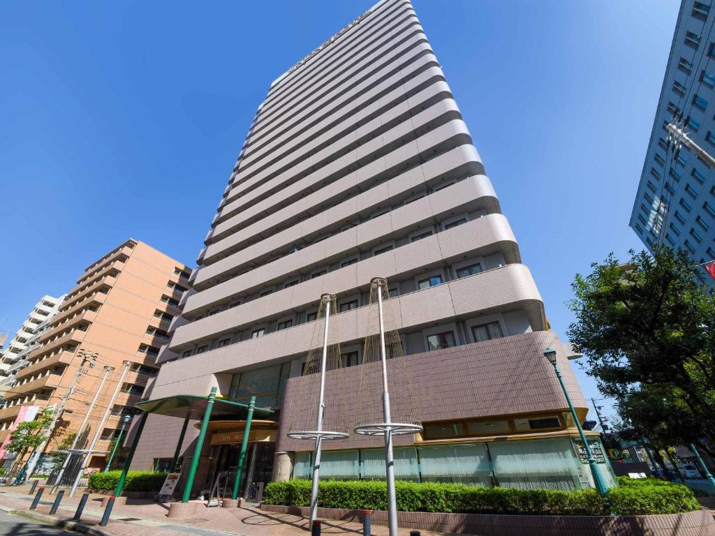 a tall building in a city with tall buildings at Kobe Sannomiya Union Hotel in Kobe