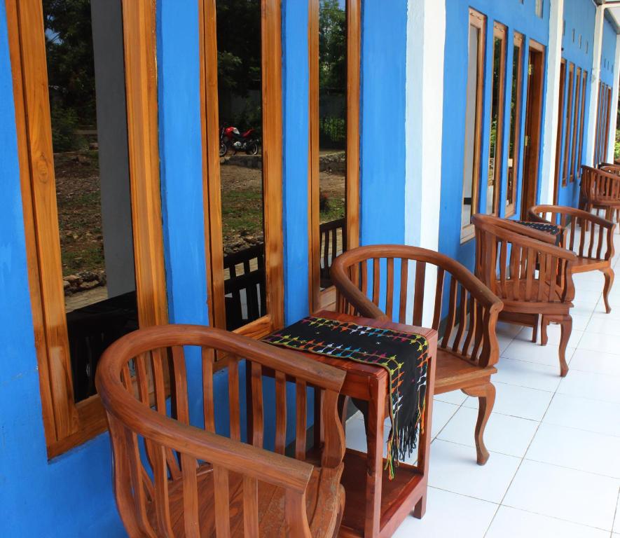 three wooden rocking chairs sitting on a porch at Danke Lodge in Labuan Bajo
