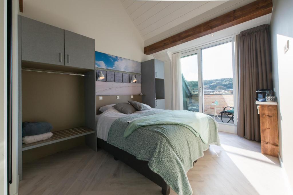 a bedroom with a bed and a large window at Duinvilla Aan de Zee B&B in Zoutelande