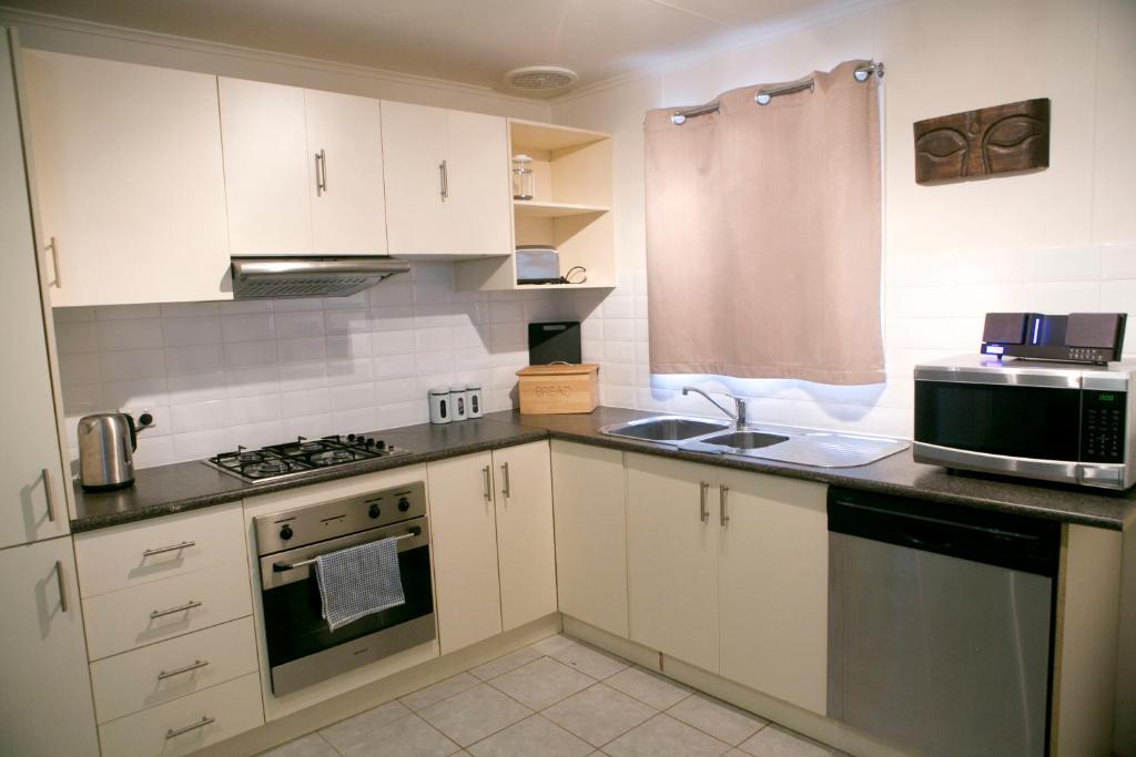 a kitchen with white cabinets and a sink and a microwave at Breakaway Views 374 ALP ST in Coober Pedy