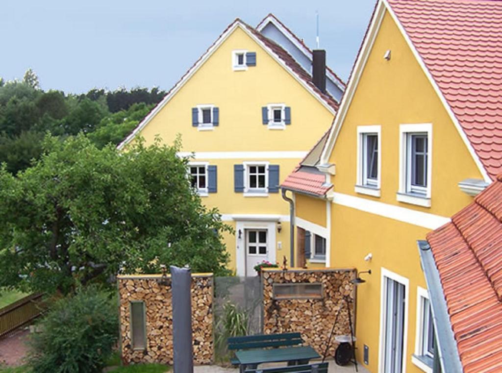 安斯巴赫的住宿－Ferienhaus Höllbachtal，前面有长凳的黄色房子