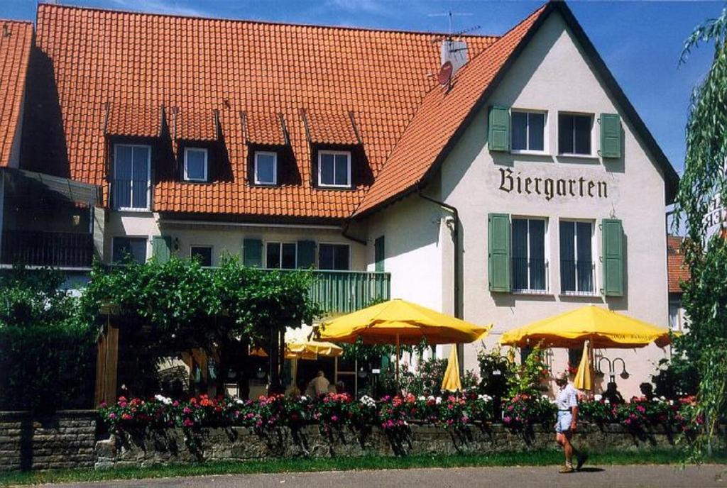 a person walking in front of a building with yellow umbrellas at Gästehaus Zehntgraf in Wipfeld