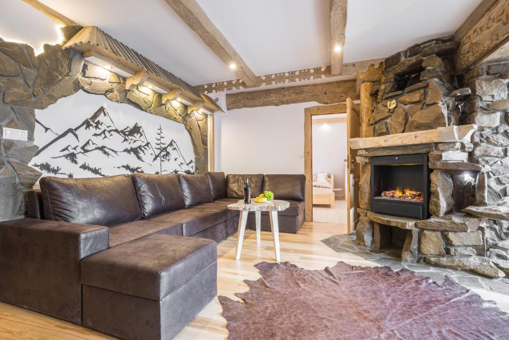 ein Wohnzimmer mit einem Sofa und einem Kamin in der Unterkunft Apartamenty Kiry Zakopane in Kościelisko