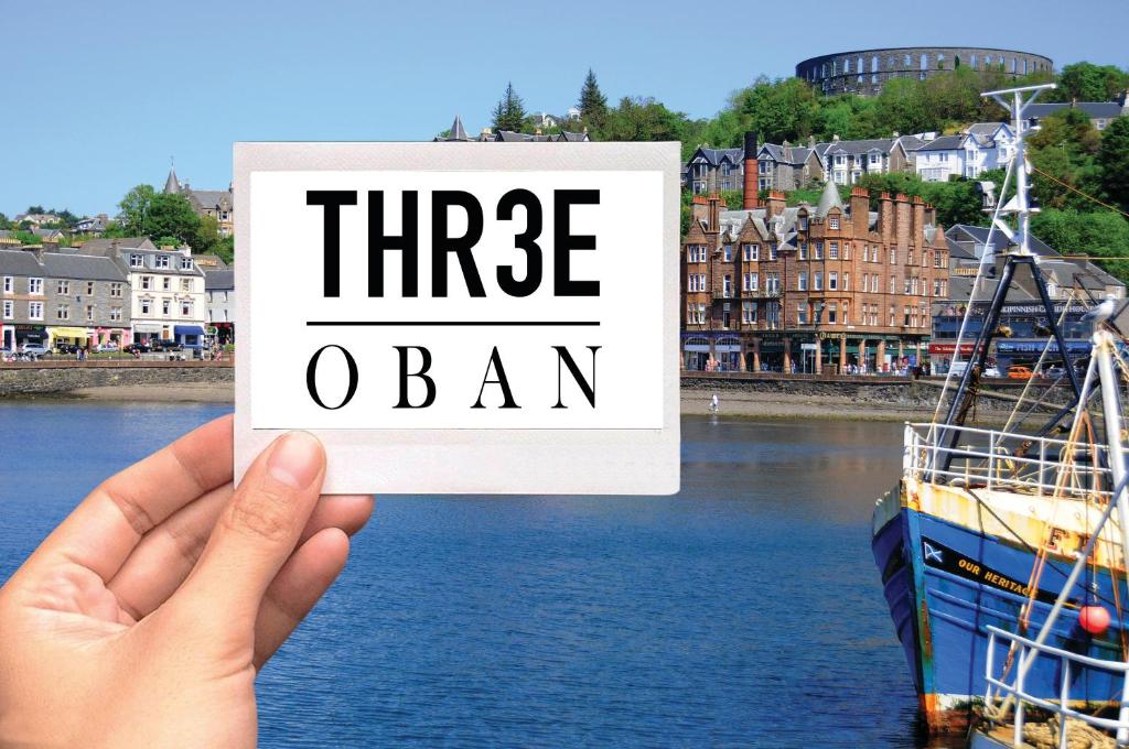 a hand holding up a sign that reads three loan at Three Oban in Oban