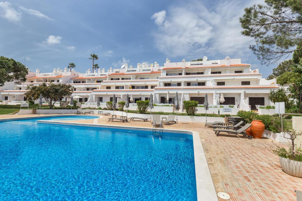 ein Hotel mit einem Pool vor einem Gebäude in der Unterkunft Apartamentos Valverde - Quinta do Lago in Quinta do Lago