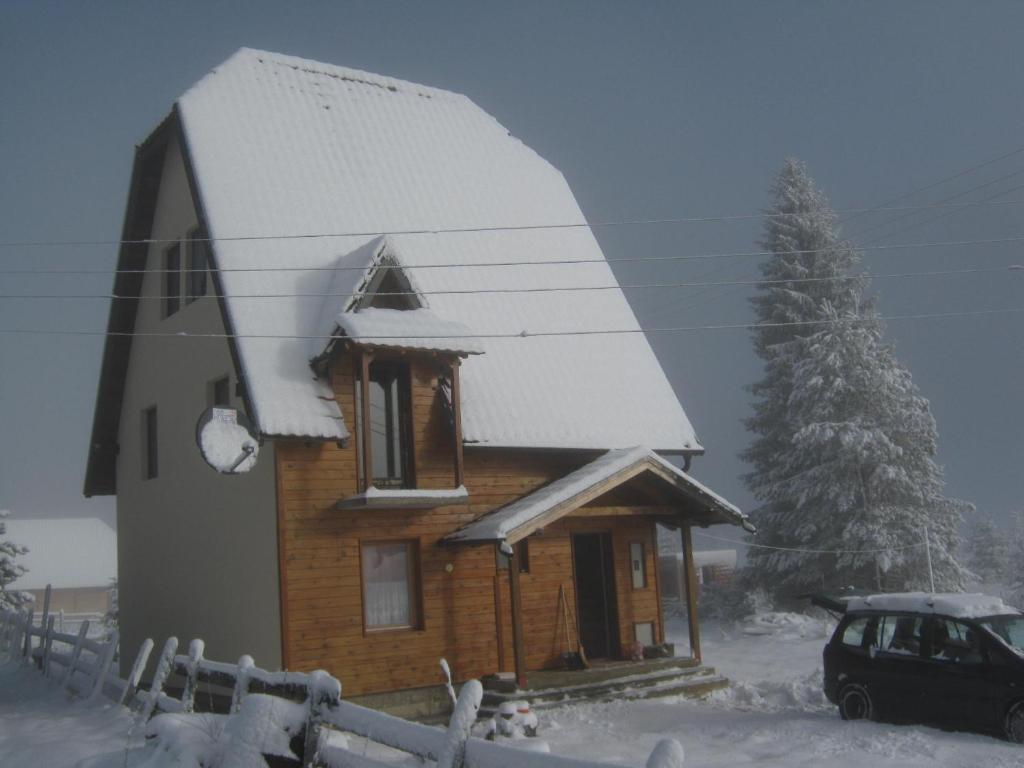 une petite maison en bois avec un toit recouvert de neige dans l'établissement Apartment Vila Fila, à Mitrovac