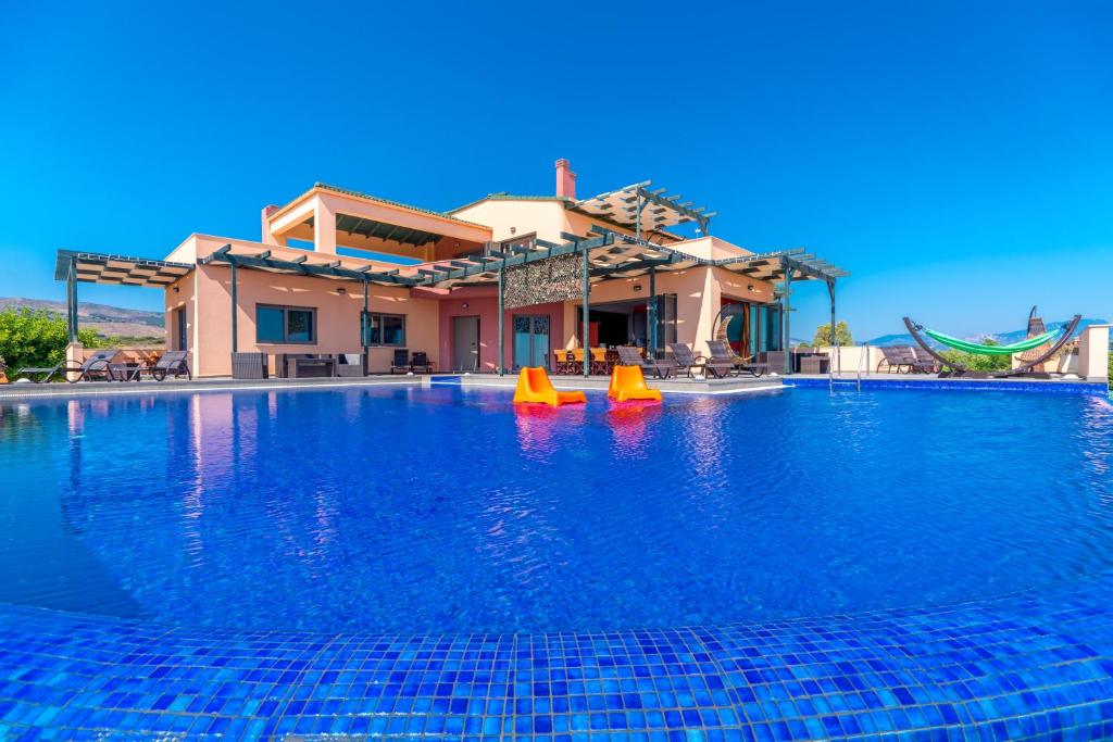 a swimming pool with blue water in front of a house at Skinos Ilivatos Eco Villa & Estate in Chavriáta