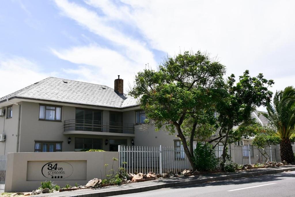 a white house with a fence in front of it at 34onlincoln Guesthouse in Bellville