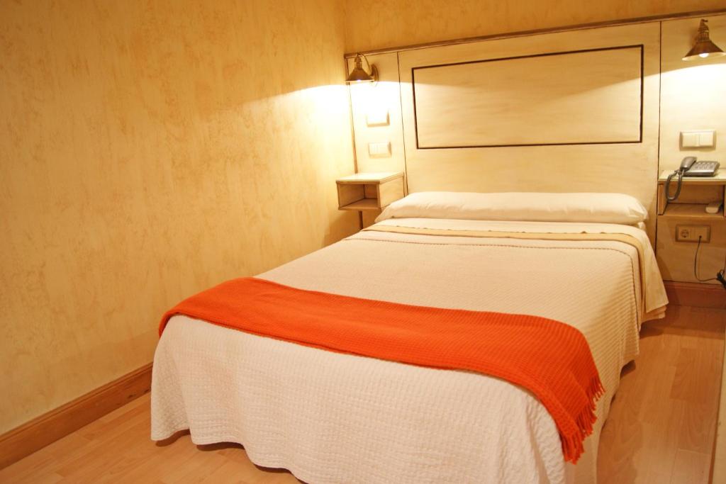 1 dormitorio con 1 cama con manta naranja y blanca en Hotel Castillo de Javier en Pamplona