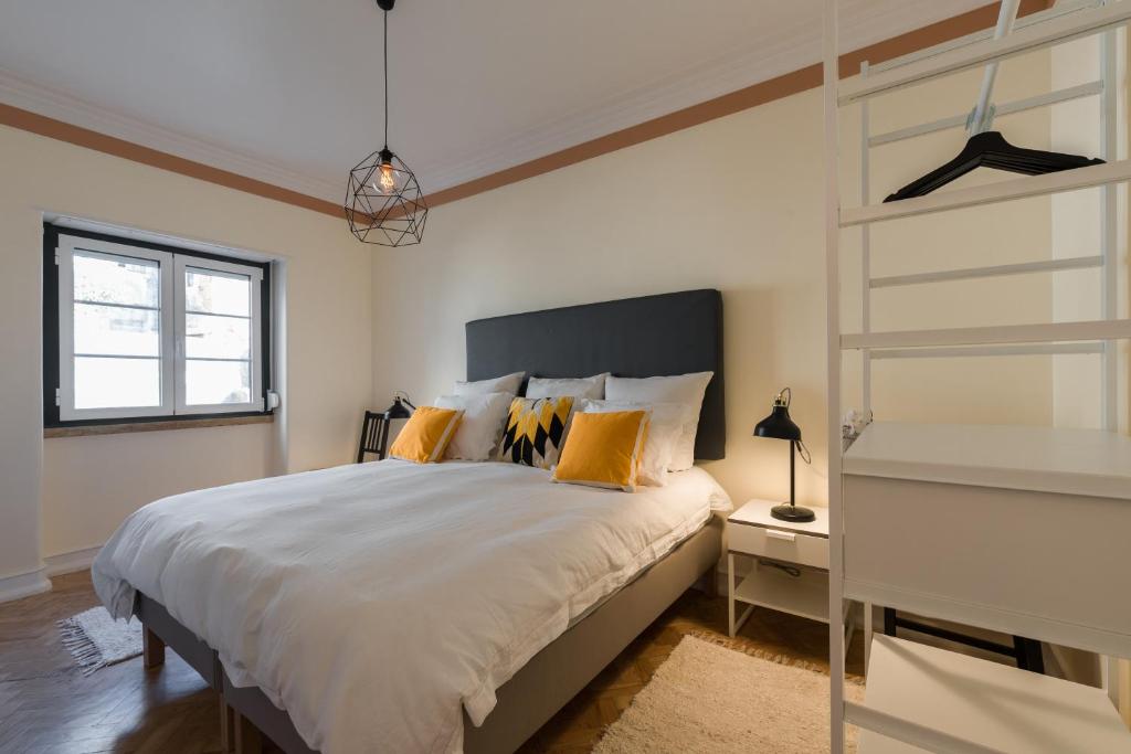 1 dormitorio con cama con almohadas de color naranja y escalera en Strategically Located, Pleasure Guaranteed en Lisboa