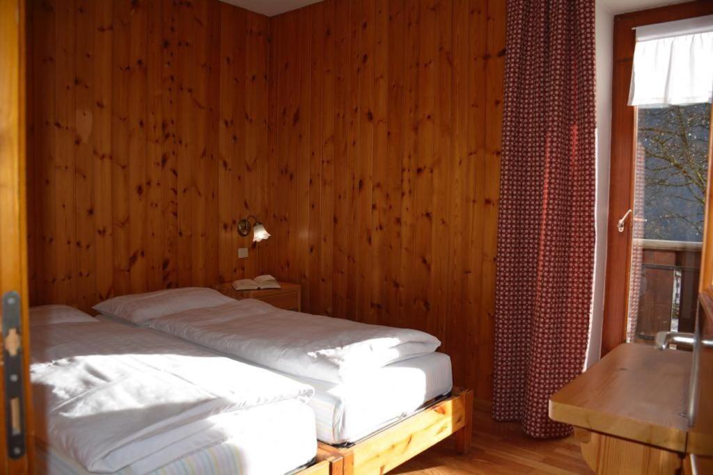 - une chambre avec un lit et un mur en bois dans l'établissement Pilat, à Vigo di Fassa