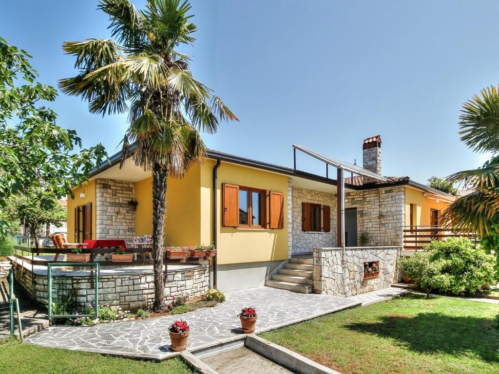 a house with a palm tree in front of it at LOVRIĆ house with apartments in Umag