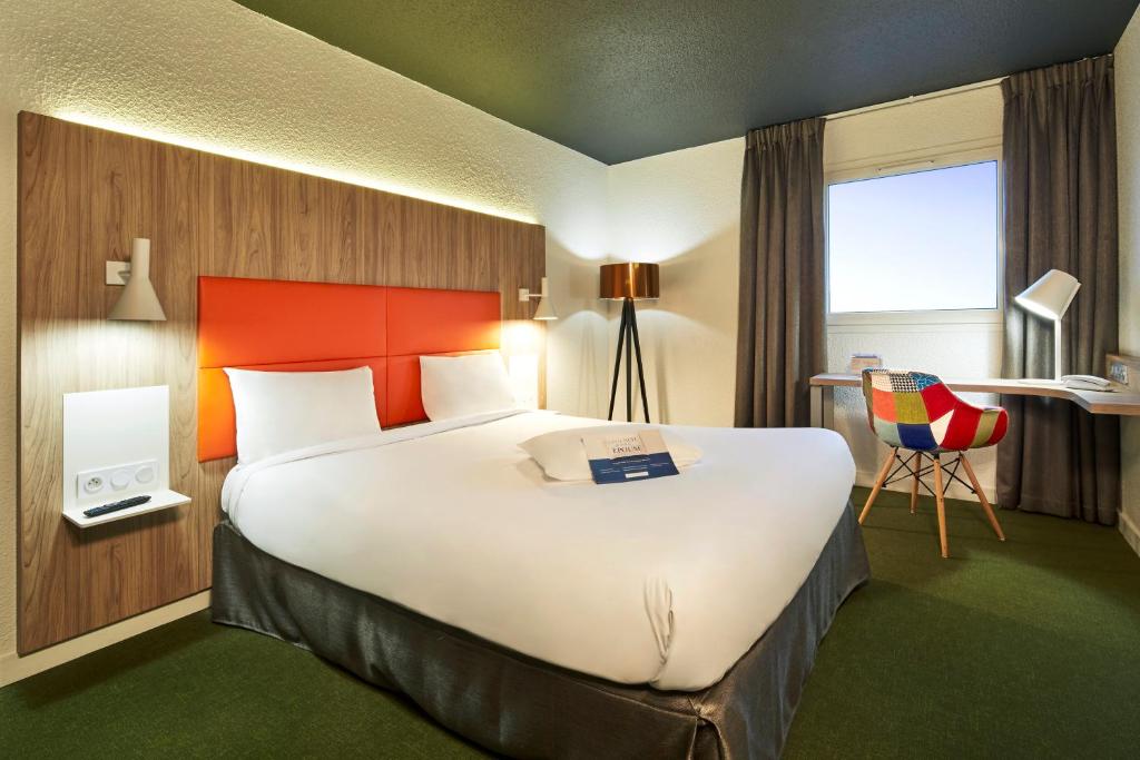 ein Hotelzimmer mit einem großen Bett und einem Schreibtisch in der Unterkunft Kyriad Clermont Ferrand Nord - Riom in Riom