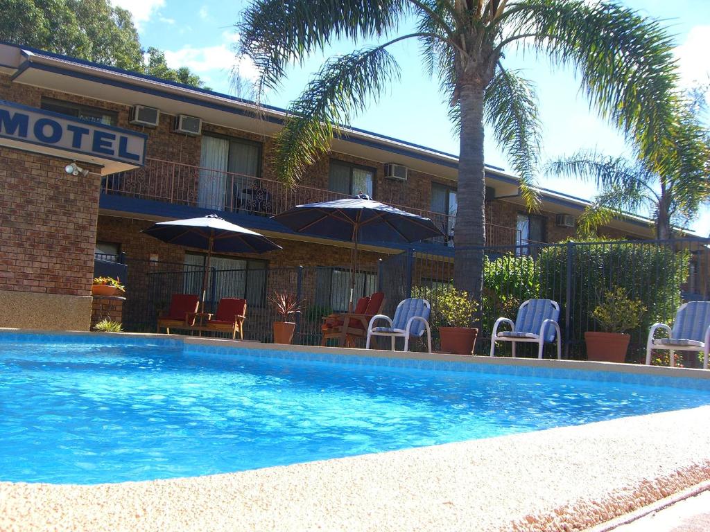 un hotel con una piscina con sillas y sombrillas en Bridge View Motel, en Gorokan