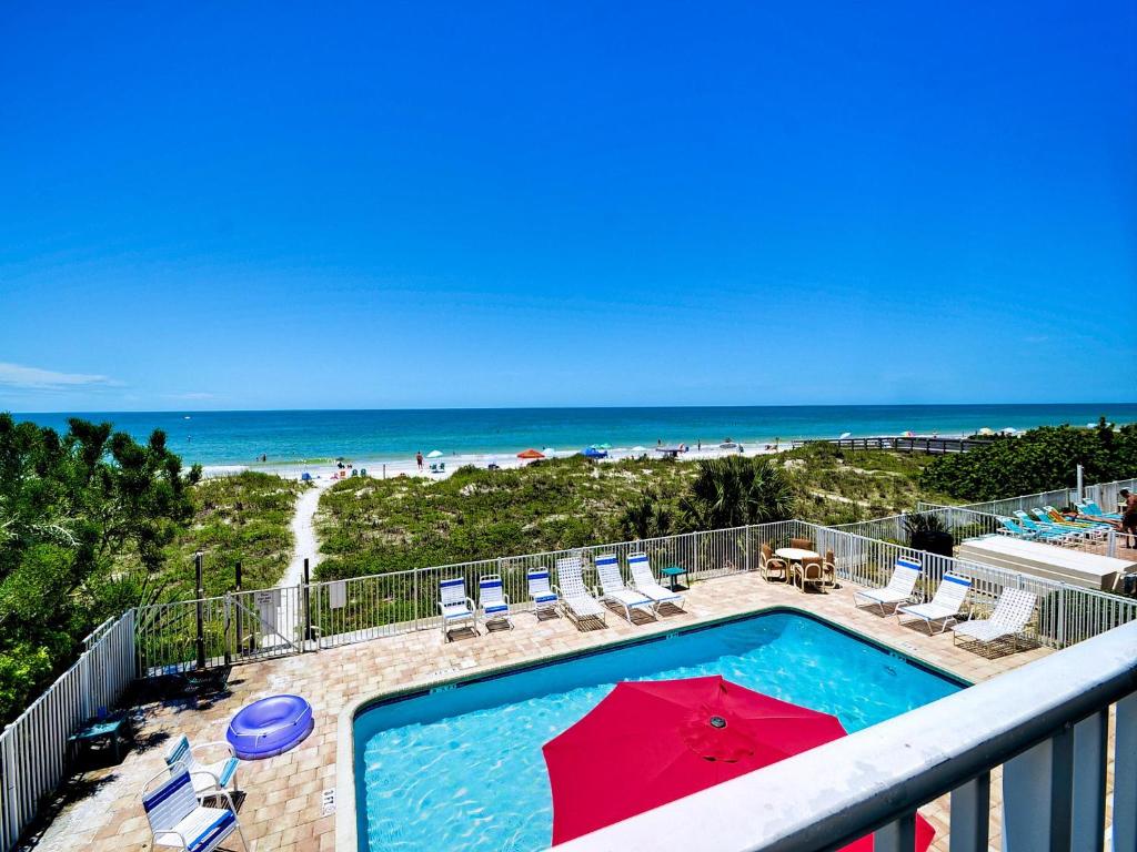 a swimming pool with a red umbrella and the beach at Beachside Hideout Unit K in Clearwater Beach