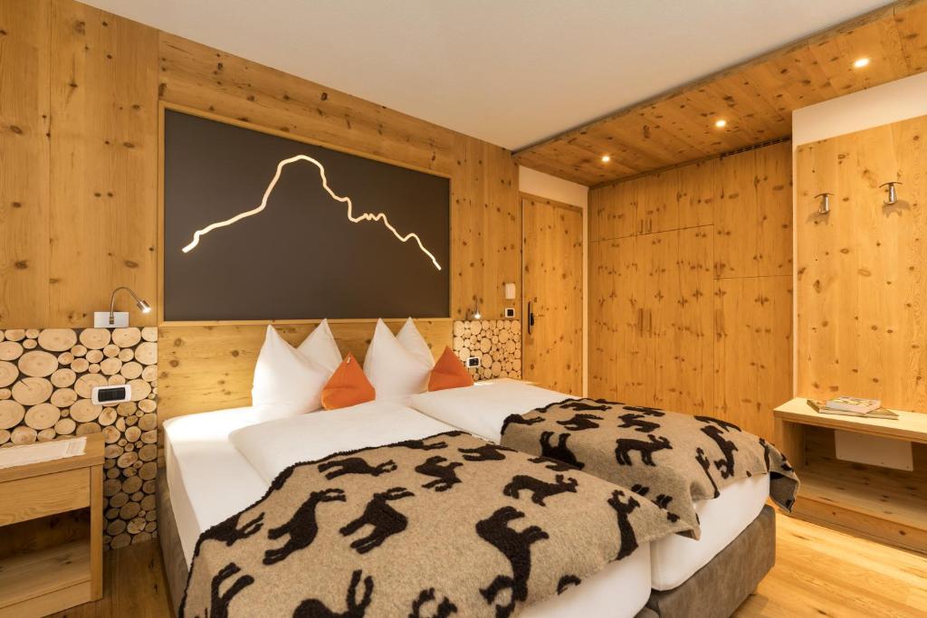 a bedroom with a bed and a screen with a mountain at Hotel Bel Sit in Corvara in Badia
