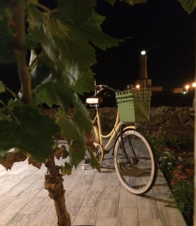 a bike with a basket parked on a sidewalk at night at B&B Casa del Faro SanVallero Adults Only in Portopalo