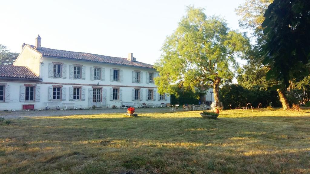 une grande maison blanche avec un arbre dans la cour dans l'établissement Domaine de Sandreau (fin XIXème siècle), à Mondonville
