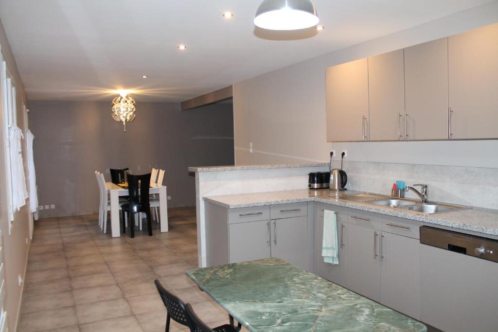 a kitchen with white cabinets and a table and chairs at Le Raboliot in La Ferté-Saint-Aubin